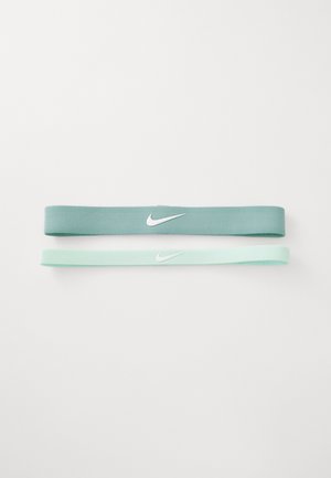 Twee Nike stoffen haarbanden in teal en licht mintgroen, elk met een witte Nike swoosh logo gecentreerd op een witte achtergrond.