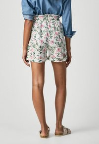 Pantalones cortos de estampado floral en blanco, con una cintura alta y cinturilla elástica. El material parece ligero con detalles de dobladillo enrollado.