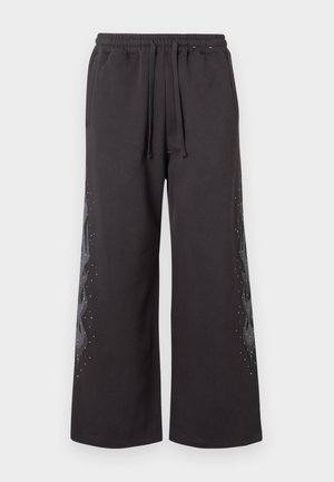 Pantaloni della tuta neri a gamba larga con vita elastica, caratterizzati da un design a fiamma grigia sul lato, rifinito con piccole pietre preziose.