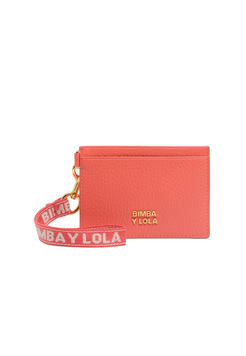 Tarjetero de cuero color coral con detalle del logo en dorado, que presenta una correa decorativa con texto en rojo y blanco. Textura suave y diseño minimalista.