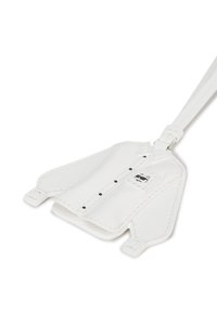 Biała skórzana metka bagażowa w kształcie koszuli, z czarnymi guzikami i łatą z wzorem. Gładka faktura z przeszywanymi akcentami.