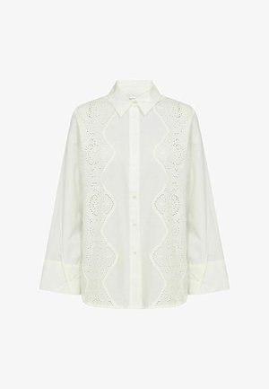 Fehér hosszú ujjú blúz elöl gombolható, hegyes gallérral és díszes virágos lyukacsos csipke panelekkel az elülső oldalak mentén.