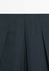 Tissu plissé gris foncé avec des coutures verticales visibles et une texture.