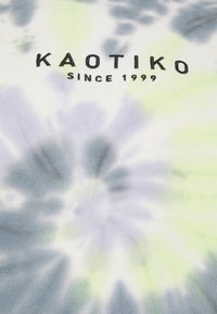 Camiseta de algodón con patrón de tie-dye en azul, verde y blanco; presenta "KAOTIKO" impreso en negro sobre "SINCE 1999."