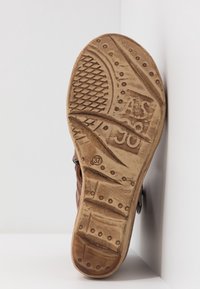 Semelle de chaussure marron usée montrant un motif de bande de roulement texturé, un marquage circulaire de taille 37, ainsi que des lettres et chiffres en relief.