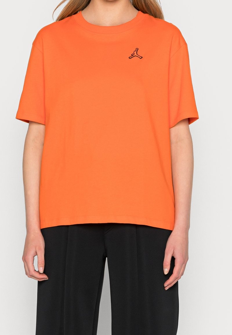 Pomarańczowy bawełniany t-shirt z krótkimi rękawami i okrągłym dekoltem. Na lewej piersi znajduje się małe czarne logo. Prosty dół koszulki.