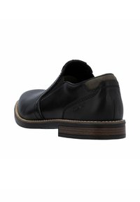 Zwarte leren schoen met een lage hak, een gladde textuur, een gebogen ontwerp en een contrasterende tan zool. Heeft stiksels en een subtiele, reliëflogo.