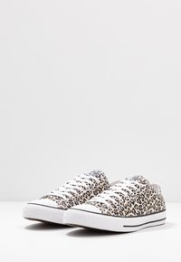 Tênis de lona com padrão leopardo, cordões brancos, solas de borracha e detalhes em preto. Design baixo e formato de bico arredondado.
