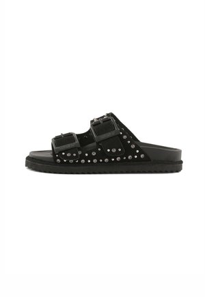 Čierna šľapka s dvoma nastaviteľnými remienkami so sponami a malými striebornými cvočkami na hornej časti, plochá podrážka s textúrovaným povrchom.