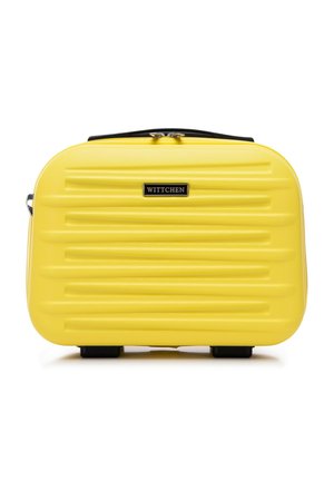 Yellow hardshell cosmetic case with horizontal ridges, black zip, and logo plate. Compact, rectangular design with bottom feet for stability.