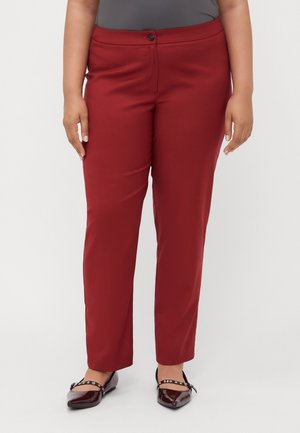 Osoba plus size nosząca bordowe spodnie z wysokim stanem o prostych nogawkach oraz ciemnoczerwone baleriny z lakierowanej skóry z paskami.