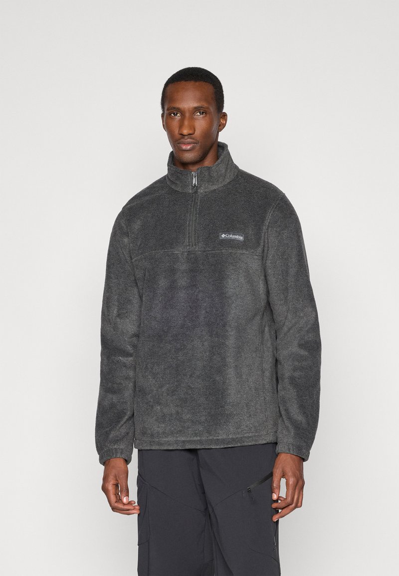 Γκρι φλις πουλόβερ με ψηλό γιακά και μισό φερμουάρ μπροστά. Περιλαμβάνει ένα μικρό λογότυπο στο στήθος και υφασμάτινη υφή.