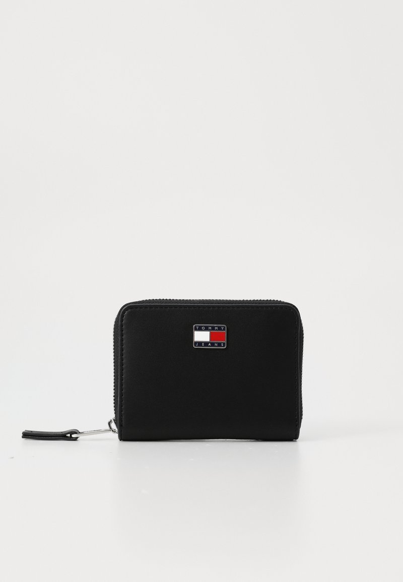 Billetera negra con cremallera en material sintético, con forma rectangular, superficie texturizada y un logo de marca en la parte frontal.