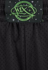 Pantaloni sportivi neri in tessuto a rete. Presentano piccole perforazioni, una vita elastica e un logo ricamato verde sull'etichetta.