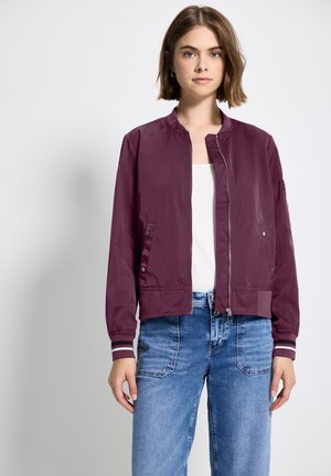 Bordeaux bomberjack met een rits aan de voorkant, geribbelde manchetten en zijzakken. Gemaakt van lichtgewicht materiaal, met een gladde textuur en een minimalistisch ontwerp.