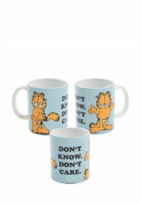 Tazze in ceramica con sfondo azzurro chiaro. Presentano un gatto cartone animato arancione, Garfield, con il testo "NON SO. NON MI INTERESSA." in grassetto nero.