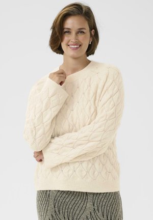 Pull en tricot couleur crème avec un motif en losanges texturé, des poignets et un ourlet côtelés, et un col rond.