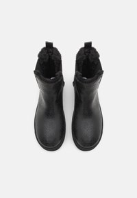 Botas negras de tobillo con una superficie texturizada que presenta un patrón de diamantes, abertura forrada de piel, y una pestaña trasera para facilitar el calzado.