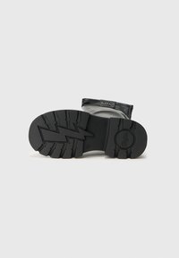 Čierna gumová podrážka s ryhovaným vzorom, vystuženou pätou a štítkom s názvom značky "BUFFALO" na hornom okraji.