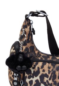 Leopard print fabric bag with a rounded shape, black zipper, and a furry gorilla keychain. Features silver hardware and a textured strap.