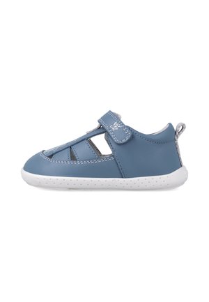 Sandalia de cuero azul con diseño de cortes, suela de goma blanca y correa de velcro. Presenta una textura suave y costuras decorativas.