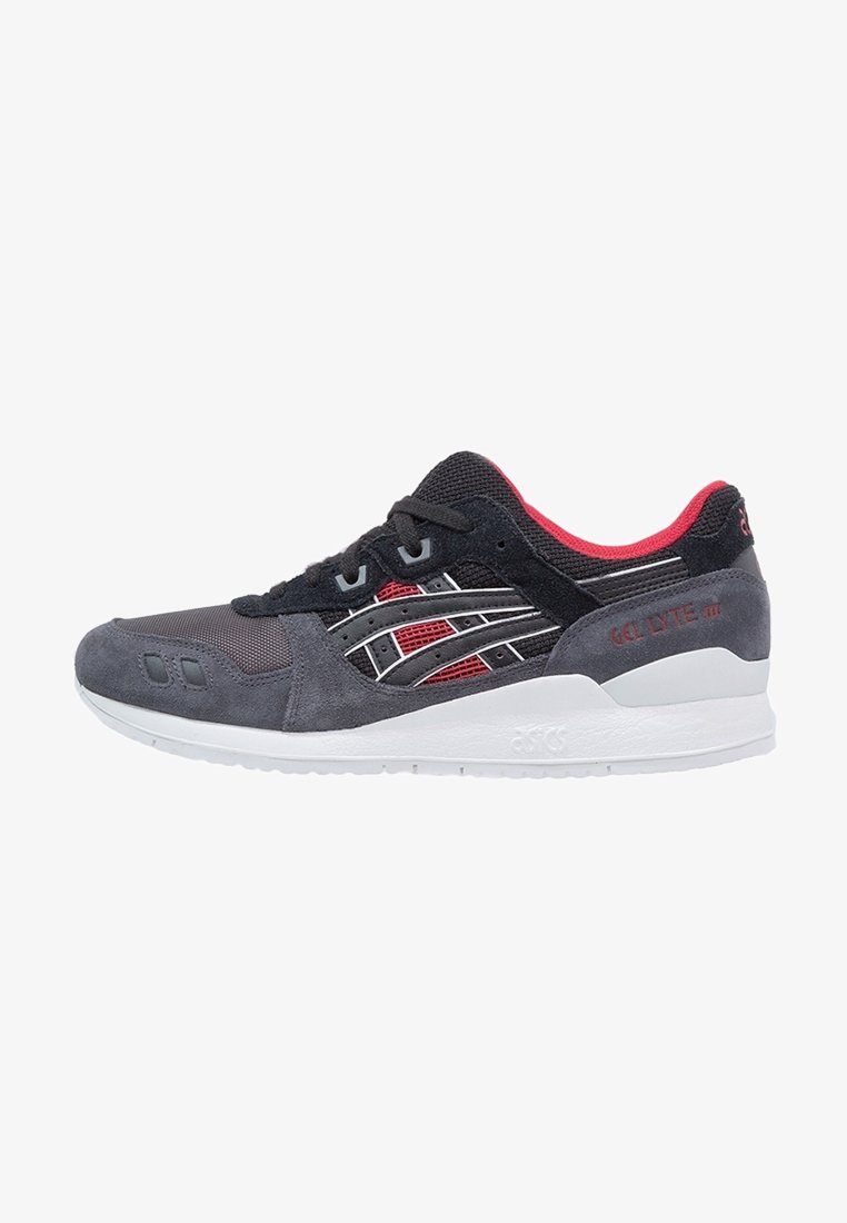 Baskets de sport noires et grises avec des accents rouges, semelle blanche, lacets à l'avant, en mesh et en daim, vues de côté.