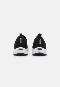 Chaussures de sport en mesh noire avec un design texturé, semelles blanches et accents dorés portant le logo et "SOFTRIDE" sur le talon.