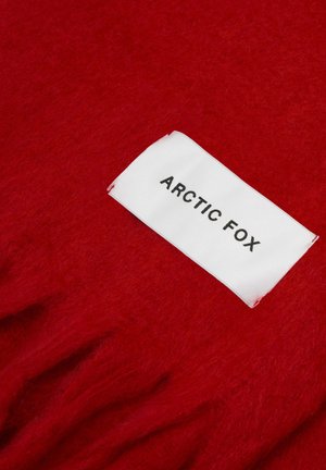 Rode wollen stof met een zachte textuur, voorzien van een wit label met de tekst "ARCTIC FOX" in zwarte letters, vastgestikt in het materiaal.