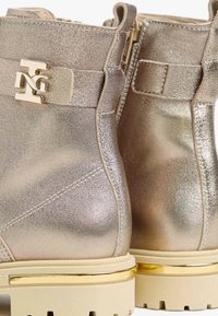 Metallic gold Ankle Boots mit strukturiertem Finish. Ausgestattet mit goldenen Hardware-Akzenten und dicken weißen Sohlen mit Profil. Mit Reißverschluss.