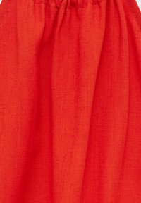 Tissu rouge avec une surface douce et texturée et un haut froncé. Le matériau semble léger et fluide, avec des plis et des drapés visibles.