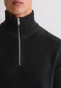 Pull zip gris foncé avec un col haut à côtes et une fermeture éclair argentée élégante, réalisé dans un tissu doux et texturé.