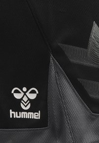 Svart och grå sportväv med Hummel-logotyp, stilren design med texturerade mönster och kontrasterande sömdetaljer.