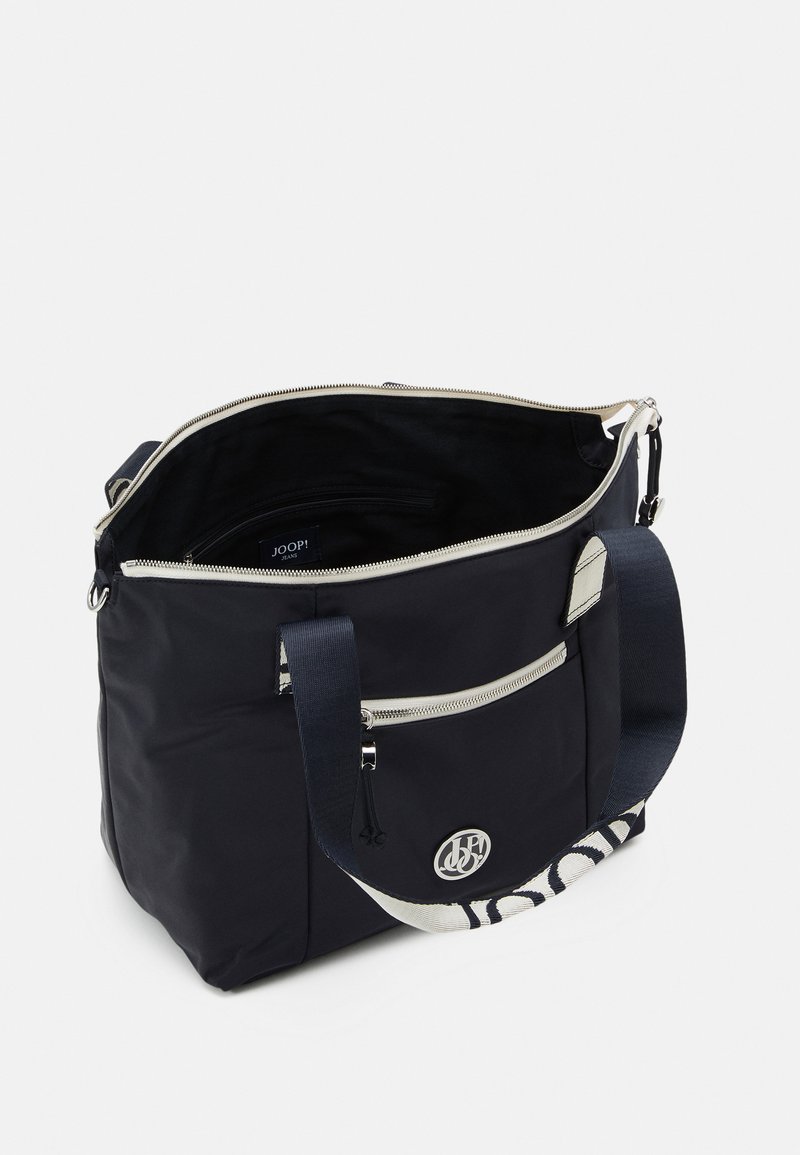 Marineblaue Nylon-Tote mit silberner Hardware, Reißverschluss oben, Vordertasche und gemustertem Schultergurt. Das Innere enthält ein Etikett und eine Tasche.