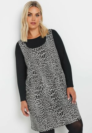 Abito leopardato bianco e nero, senza maniche con scollatura rotonda, sovrapposto a una maglietta nera a manica lunga, con una vestibilità ampia e tessuto testurizzato.