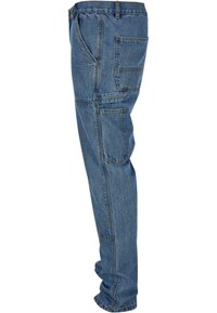 Denim jeans in medium blue with a straight leg cut, featuring multiple pockets and reinforced stitching along the seams.
