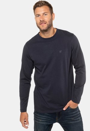 Marineblauwe longsleeve t-shirt met ronde hals, gemaakt van een zachte katoenmix, met een subtiele logo op de borst. Gecombineerd met spijkerbroeken.