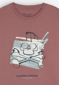 Camiseta de algodón en rosa empolvado con un diseño gráfico que presenta un skull, huesos cruzados y formas abstractas en azul y negro.