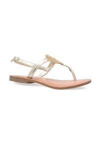 Guld metallic flade sandaler har et T-strop design, klare rhinestone detaljer og en beige fodseng med hvid syning.