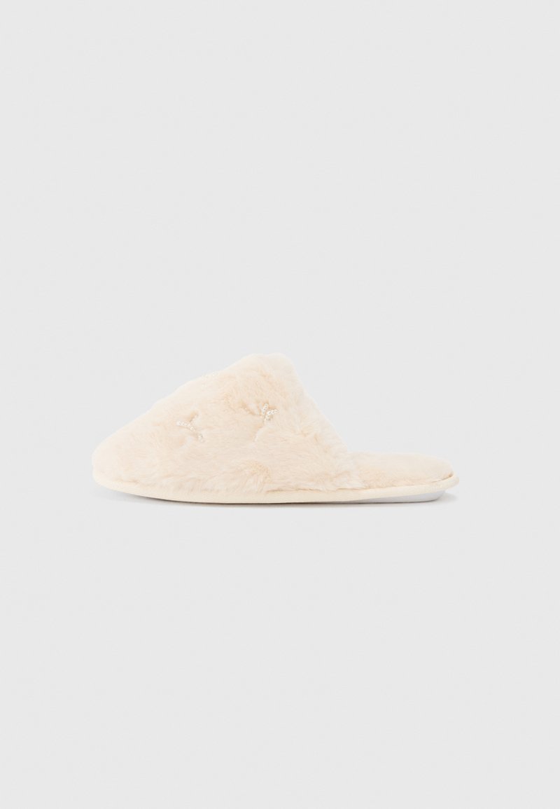 Chinelo felpudo, de cor creme, com uma textura suave, design de ponta aberta e sutis detalhes bordados na parte superior.