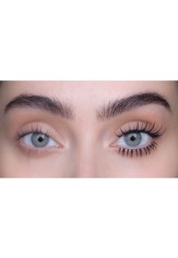 Primer plano de dos ojos; uno con pestañas naturales y el otro con pestañas largas y definidas de color negro. Ambos ojos tienen una textura marrón claro y clara.