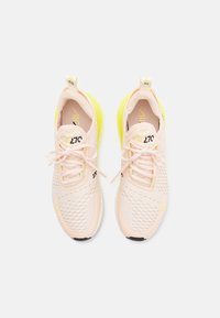Paire de chaussures de sport rose clair avec dessus en mesh, lacets à l'avant, et talons rembourrés jaune vif, vues de dessus sur un fond blanc.