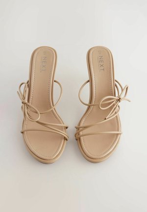 Sandali flat nudi con design a strisce sottili, realizzati in materiale sintetico morbido, con punta quadrata e dettagli legati ai lati.