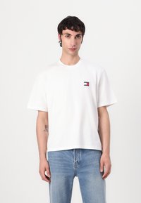 Hvid bomulds T-shirt med rund hals, korte ærmer og et lille broderet logo i rød og blå på venstre bryst. Casual fit.