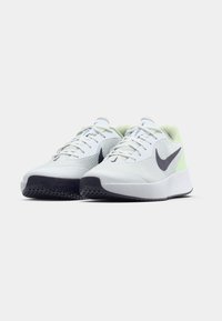 Ζευγάρι λευκών αθλητικών παπουτσιών Nike με μαύρο λογότυπο swoosh, λευκές κορδόνες και μαύρες σόλες σε λευκό φόντο.