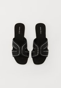 Sandale negre cu un strat de suede moale, cu accente metalice și un design unic cu curele suprapuse. Talpă plată pentru confort.
