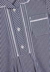 Marineblaues und weißes karriertes Hemd mit Kragen, herzförmigen Knöpfen, weißen Details und einer einzelnen Brusttasche. Hergestellt aus weichem Stoff.