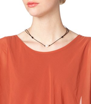 Zwarte koordketting met twee witte parels en zwarte kralen, gedragen met een roestkleurig top.