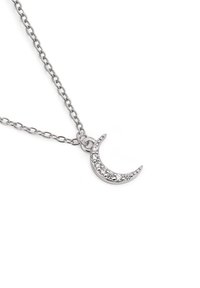 Collier en argent arborant un pendentif en forme de croissant de lune orné de strass, suspendu à une chaîne délicate avec un design de maillon simple.