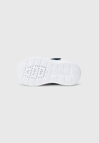 Hvit skosåle med teksturert grep, med sirkulære utskjæringer og et mønstret design for bedre friksjon, merket med "Geox".