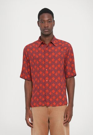 Chemise à manches courtes rouge avec un motif géométrique bleu marine. Dotée d'un col classique et d'une fermeture à boutons. Texture de tissu lisse.